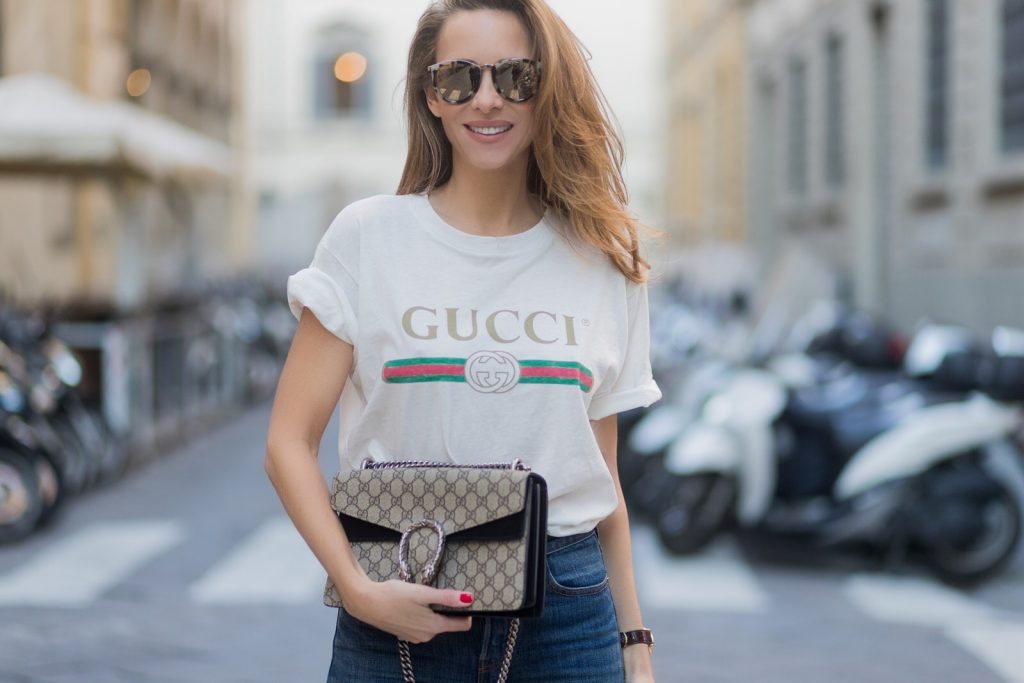 FLORENCE, ITALY - JANUARY 11: German fashion blogger and model Alexandra Lapp is wearing retro vibe Gucci printed cotton T-shirt, featuring a throwback Gucci logo, this piece features distressed detailing around the neckline, slim fit Wedgie Icon Fit Jeans from Levi’s, suede /buckskin leather trench coat from Oui, Dionysus GG Supreme Medium Gucci shoulder bag, Le Specs sunglasses, red pumps from Gianvito Rossi on January 11, 2017 in Florence, Italy. (Photo by Christian Vierig/Getty Images) *** Local Caption *** Alexandra Lapp