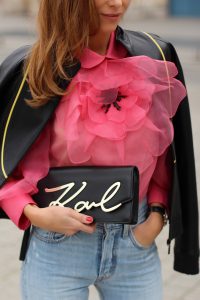 KARL IN PARIS, FRANCE - MARCH 04: Alexandra Lapp wearing a K Karl clutch bag with a gold application of Karl Lagerfeld's personal signature by Karl Lagerfeld, a pink Gucci blouse which is slightly transparent and decorated with a big blooming flower, a light blue Levi's 501 skinny jeans with button fly in the classic five-pocket design, a leather jacket with yellow details by Pearl & Rubies and pink pumps by Christian Louboutin on March 4, 2017 in Paris, France.