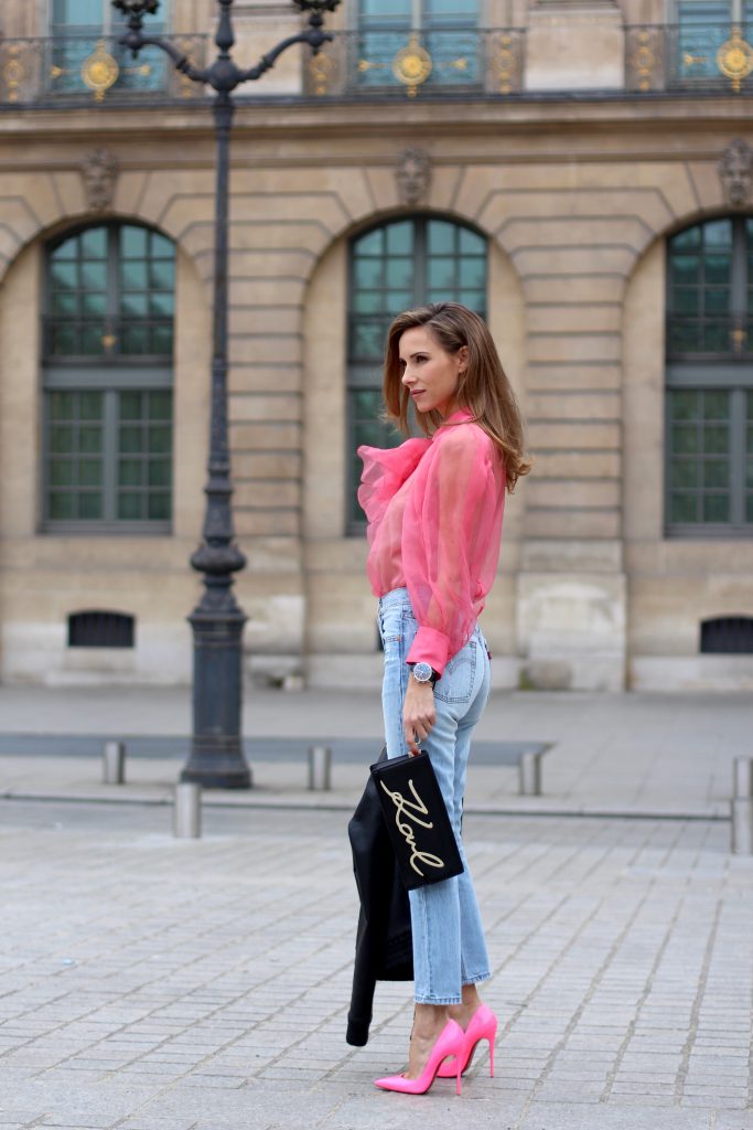 KARL IN PARIS, FRANCE - MARCH 04: Alexandra Lapp wearing a K Karl clutch bag with a gold application of Karl Lagerfeld's personal signature by Karl Lagerfeld, a pink Gucci blouse which is slightly transparent and decorated with a big blooming flower, a light blue Levi's 501 skinny jeans with button fly in the classic five-pocket design, a leather jacket with yellow details by Pearl & Rubies and pink pumps by Christian Louboutin on March 4, 2017 in Paris, France. 