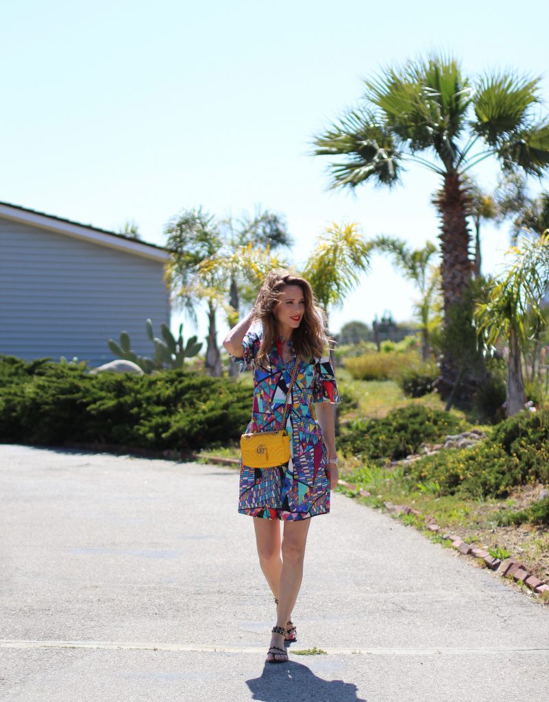 Malibu, Los Angeles; Model and fashion blogger Alexandra Lapp wearing a colorful dress by La Martina, the Polo brand, sandals from Saint Laurent in black with golden rock studs, red lipstick from MAC, a yellow Gucci GG Marmont bag, IWC Da Vinci Automatic 36 watch in 18-carat red gold with diamonds and jewelry from AYS (Art Youth Society) in Malibu on April 17, 2017 in Los Angeles, California.
