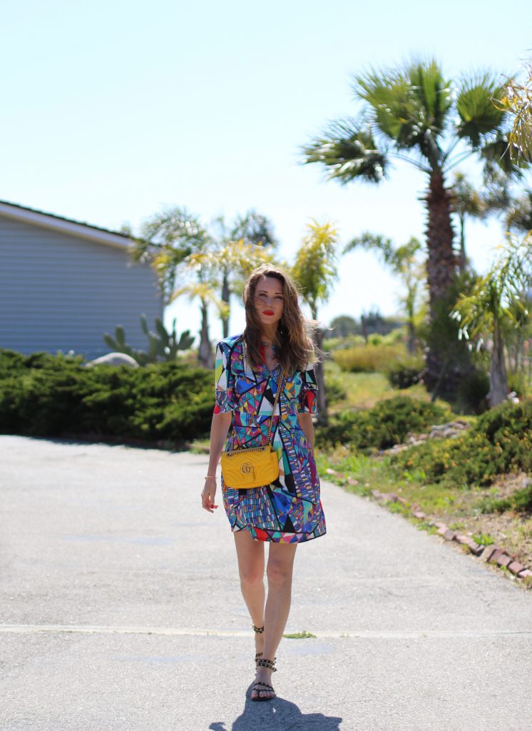 Malibu, Los Angeles; Model and fashion blogger Alexandra Lapp wearing a colorful dress by La Martina, the Polo brand, sandals from Saint Laurent in black with golden rock studs, red lipstick from MAC, a yellow Gucci GG Marmont bag, IWC Da Vinci Automatic 36 watch in 18-carat red gold with diamonds and jewelry from AYS (Art Youth Society) in Malibu on April 17, 2017 in Los Angeles, California.