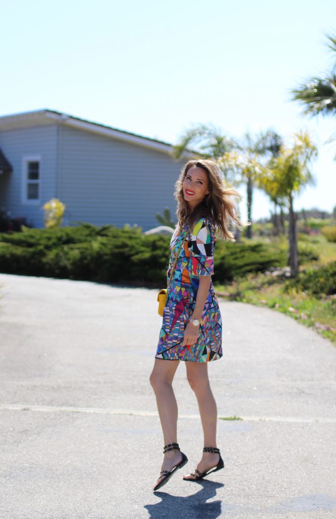 Malibu, Los Angeles; Model and fashion blogger Alexandra Lapp wearing a colorful dress by La Martina, the Polo brand, sandals from Saint Laurent in black with golden rock studs, red lipstick from MAC, a yellow Gucci GG Marmont bag, IWC Da Vinci Automatic 36 watch in 18-carat red gold with diamonds and jewelry from AYS (Art Youth Society) in Malibu on April 17, 2017 in Los Angeles, California.