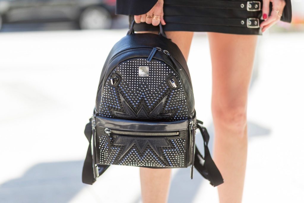Model and fashion blogger Alexandra Lapp wearing an MCM backpack, high waist mini skirt in black leather with silver buckles from Manokhi Leather, white linen striped zipped top from Karl Lagerfeld, with a leather sunglasses application, Dior Slingback pumps in black patent calfskin leather and J'Adior ribbon with a 10 cm heel, Dior choker around the neck, Diormania sunglasses by Dior, Saint Laurent jacket and the Dual Stark Cyber backpack from MCM with techno-graphic details, made from specially foil-coated black razor cowhide, polished off with applications and studs a plus the front pocket zips off to create a separate crossbody or clutch, IWC Da Vinci Automatic 36 watch in 18-carat red gold with diamonds and jewelry from AYS (Art Youth Society) on April 20, 2017 on Rodeo Drive in Los Angeles, California.