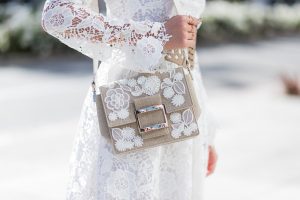 Model and fashion blogger Alexandra Lapp wearing the Roger Vivier Viv' bag which is crafted from linen with lace detailing and features a new slightly rounded buckle and a leather strap, white Zouze dress, waist belt in beige and white leather from Azzedine Alaia, white sandals from Azzedine Alaia, Chanel sunglasses with pearls, IWC Da Vinci Automatic 36 watch in 18-carat red gold with diamonds and jewelry from AYS (Art Youth Society) on April 20, 2017 in Los Angeles, California.