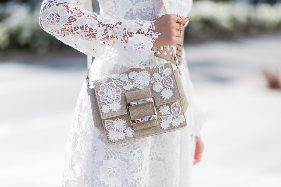 Model and fashion blogger Alexandra Lapp wearing the Roger Vivier Viv' bag which is crafted from linen with lace detailing and features a new slightly rounded buckle and a leather strap, white Zouze dress, waist belt in beige and white leather from Azzedine Alaia, white sandals from Azzedine Alaia, Chanel sunglasses with pearls, IWC Da Vinci Automatic 36 watch in 18-carat red gold with diamonds and jewelry from AYS (Art Youth Society) on April 20, 2017 in Los Angeles, California.