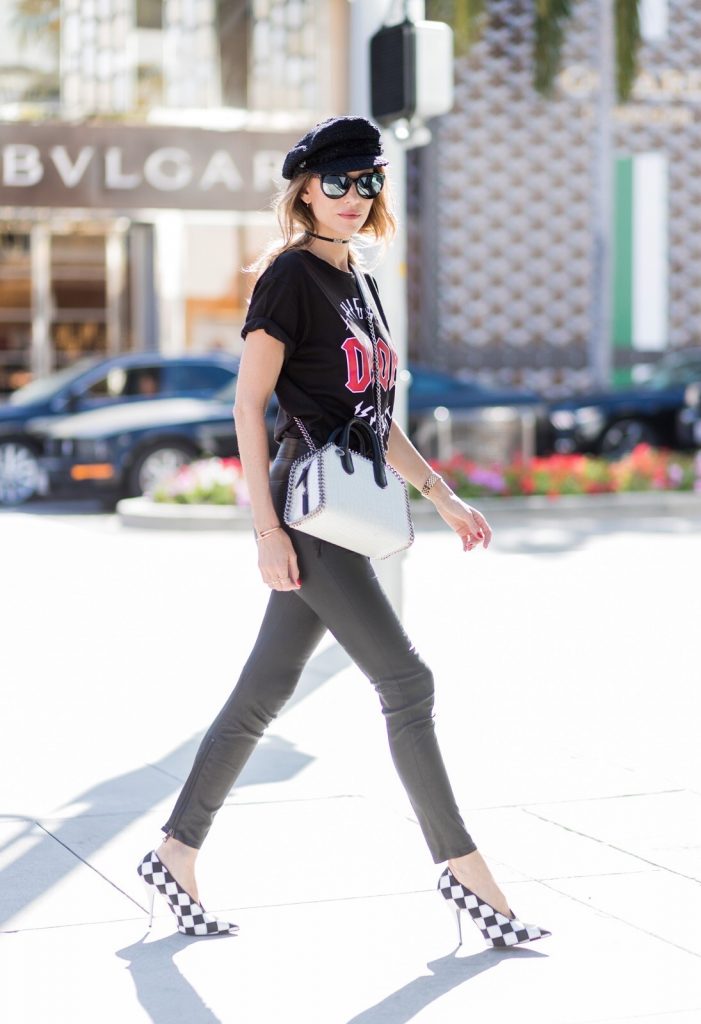 Model and fashion blogger Alexandra Lapp wearing V-Neck-Pumps, a LACE FRONT SKINNY LEATHER PANTS by Unravel, Dior High Voltage T-Shirt from Ecntrc, black and white vegan patent Stella McCartney check pointed toe V-neck-pumps with high-cut toe box, Falabella Box mini faux-leather cross-body bag in black and white, Chanel cap, Diormania sunglasses by Dior and Dior choker, IWC Da Vinci Automatic 36 watch in 18-carat red gold with diamonds and jewelry from AYS (Art Youth Society) on April 20, 2017 in Los Angeles, California.