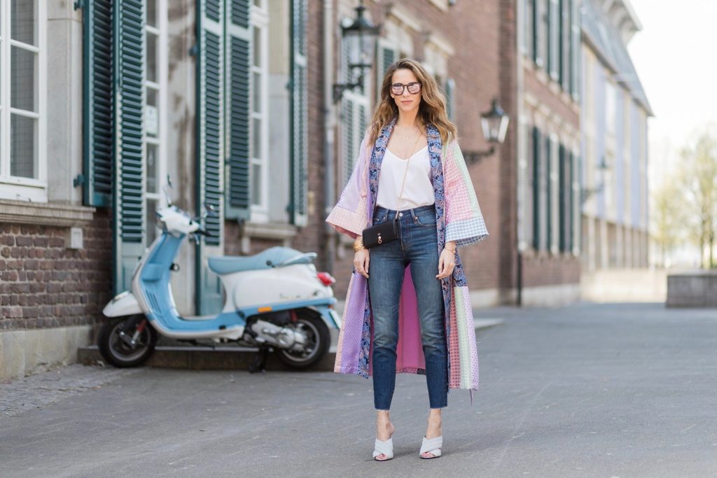 Model and fashion blogger Alexandra Lapp wearing a printed kimono / panel robe from Natasha Zinko, slim fit high waist Jeans from Rag & Bone, Mules by Gucci with open-toe-silhouette in glittery silver grey, white silk tank top from Jadicted, colorful mirrored sunglasses from Les Specs, black leather ring detail continental purse bag from Fendi featuring an embossed logo, a press stud fastening, multiple interior card slots, an interior zipped compartment and a gold-tone chain shoulder strap on March 30, 2017 in Duesseldorf, Germany.