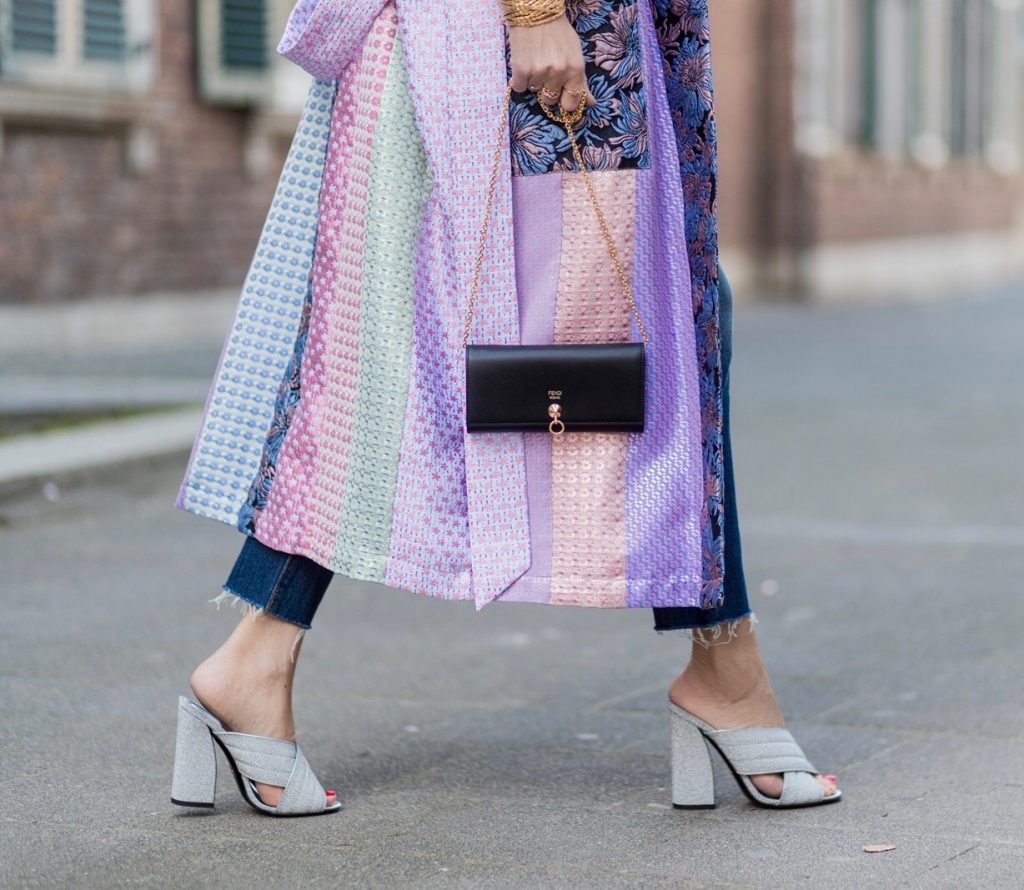 Model and fashion blogger Alexandra Lapp wearing a printed kimono / panel robe from Natasha Zinko, slim fit high waist Jeans from Rag & Bone, Mules by Gucci with open-toe-silhouette in glittery silver grey, white silk tank top from Jadicted, colorful mirrored sunglasses from Les Specs, black leather ring detail continental purse bag from Fendi featuring an embossed logo, a press stud fastening, multiple interior card slots, an interior zipped compartment and a gold-tone chain shoulder strap on March 30, 2017 in Duesseldorf, Germany.