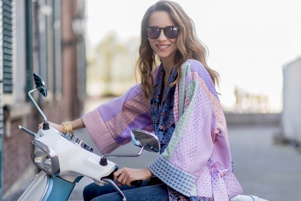 Model and fashion blogger Alexandra Lapp wearing a printed kimono / panel robe from Natasha Zinko, slim fit high waist Jeans from Rag & Bone, Mules by Gucci with open-toe-silhouette in glittery silver grey, white silk tank top from Jadicted, colorful mirrored sunglasses from Les Specs, black leather ring detail continental purse bag from Fendi featuring an embossed logo, a press stud fastening, multiple interior card slots, an interior zipped compartment and a gold-tone chain shoulder strap on March 30, 2017 in Duesseldorf, Germany.