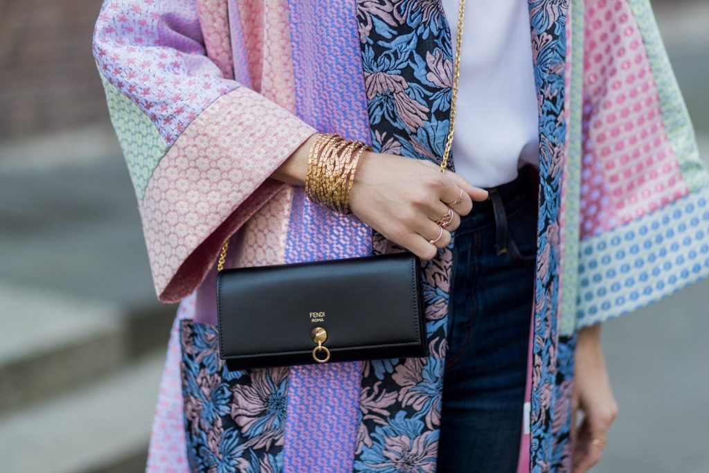 Model and fashion blogger Alexandra Lapp wearing a printed kimono / panel robe from Natasha Zinko, slim fit high waist Jeans from Rag & Bone, Mules by Gucci with open-toe-silhouette in glittery silver grey, white silk tank top from Jadicted, colorful mirrored sunglasses from Les Specs, black leather ring detail continental purse bag from Fendi featuring an embossed logo, a press stud fastening, multiple interior card slots, an interior zipped compartment and a gold-tone chain shoulder strap on March 30, 2017 in Duesseldorf, Germany.