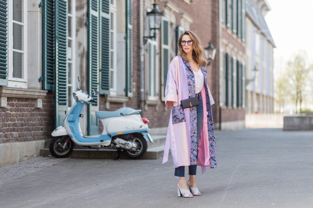 Model and fashion blogger Alexandra Lapp wearing a printed kimono / panel robe from Natasha Zinko, slim fit high waist Jeans from Rag & Bone, Mules by Gucci with open-toe-silhouette in glittery silver grey, white silk tank top from Jadicted, colorful mirrored sunglasses from Les Specs, black leather ring detail continental purse bag from Fendi featuring an embossed logo, a press stud fastening, multiple interior card slots, an interior zipped compartment and a gold-tone chain shoulder strap on March 30, 2017 in Duesseldorf, Germany.