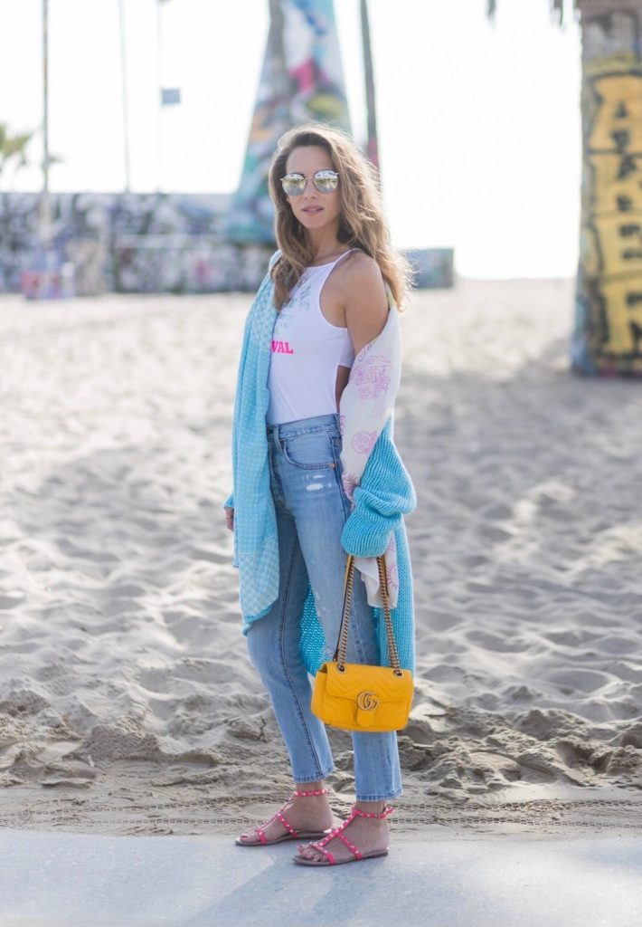 Model and fashion blogger Alexandra Lapp enjoying the beach life, wearing Levis skinny jeans in light blue with a vintage optic, a body from Patrizia Pepe in sensitive white lycra with iridescent and fluorescent laminated Welcome to the Desert Festival print, a long cashmere cardican / coatigan from Heartbreaker in turquoise, a pashmina scarf from Heartbreaker, Valentino Rockstud sandals in pink, a yellow Gucci GG Marmont bag, silver mirrored sunglasses by Le Specs, IWC Da Vinci Automatic 36 watch in 18-carat red gold with diamonds and jewelry from AYS (Art Youth Society) in Venice Beach on April 19, 2017 in Los Angeles, California.