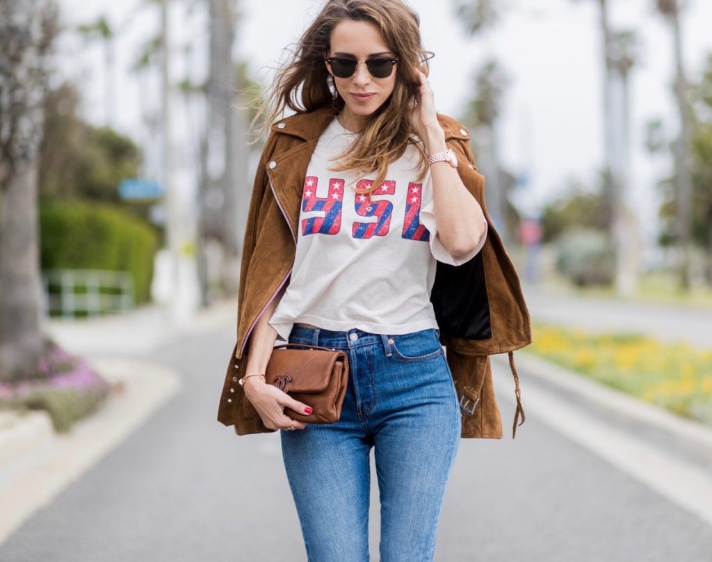 Model and fashion blogger Alexandra Lapp wearing a suede biker Jacket from Tigha, Wedgie Icon Fit jeans, slim fit in dark blue by Levi's, washed rose cotton YSL USA cropped T-shirt from Saint Laurent featuring a ribbed round neck, dropped shoulders, short sleeves, a print to the front, a straight hem and a loose fit, Christian Louboutin pumps 'So Kate' in brown cognac, Chanel bag 2.55 with a big Coco Chanel Logo, Ray Ban Clubmaster sunglasses, IWC Da Vinci Automatic 36 watch in 18-carat red gold with diamonds and jewelry from AYS (Art Youth Society) on April 19, 2017 in Los Angeles, California.