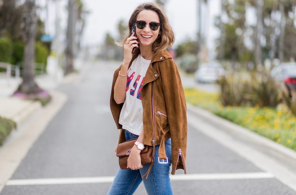Model and fashion blogger Alexandra Lapp wearing a suede biker Jacket from Tigha, Wedgie Icon Fit jeans, slim fit in dark blue by Levi's, washed rose cotton YSL USA cropped T-shirt from Saint Laurent featuring a ribbed round neck, dropped shoulders, short sleeves, a print to the front, a straight hem and a loose fit, Christian Louboutin pumps 'So Kate' in brown cognac, Chanel bag 2.55 with a big Coco Chanel Logo, Ray Ban Clubmaster sunglasses, IWC Da Vinci Automatic 36 watch in 18-carat red gold with diamonds and jewelry from AYS (Art Youth Society) on April 19, 2017 in Los Angeles, California.
