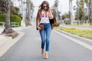 Model and fashion blogger Alexandra Lapp wearing a suede biker Jacket from Tigha, Wedgie Icon Fit jeans, slim fit in dark blue by Levi's, washed rose cotton YSL USA cropped T-shirt from Saint Laurent featuring a ribbed round neck, dropped shoulders, short sleeves, a print to the front, a straight hem and a loose fit, Christian Louboutin pumps 'So Kate' in brown cognac, Chanel bag 2.55 with a big Coco Chanel Logo, Ray Ban Clubmaster sunglasses, IWC Da Vinci Automatic 36 watch in 18-carat red gold with diamonds and jewelry from AYS (Art Youth Society) on April 19, 2017 in Los Angeles, California.