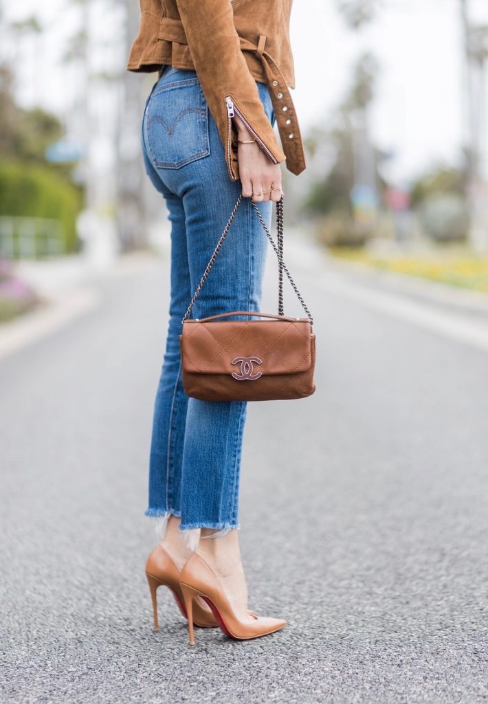 Model and fashion blogger Alexandra Lapp wearing a suede biker Jacket from Tigha, Wedgie Icon Fit jeans, slim fit in dark blue by Levi's, washed rose cotton YSL USA cropped T-shirt from Saint Laurent featuring a ribbed round neck, dropped shoulders, short sleeves, a print to the front, a straight hem and a loose fit, Christian Louboutin pumps 'So Kate' in brown cognac, Chanel bag 2.55 with a big Coco Chanel Logo, Ray Ban Clubmaster sunglasses, IWC Da Vinci Automatic 36 watch in 18-carat red gold with diamonds and jewelry from AYS (Art Youth Society) on April 19, 2017 in Los Angeles, California.