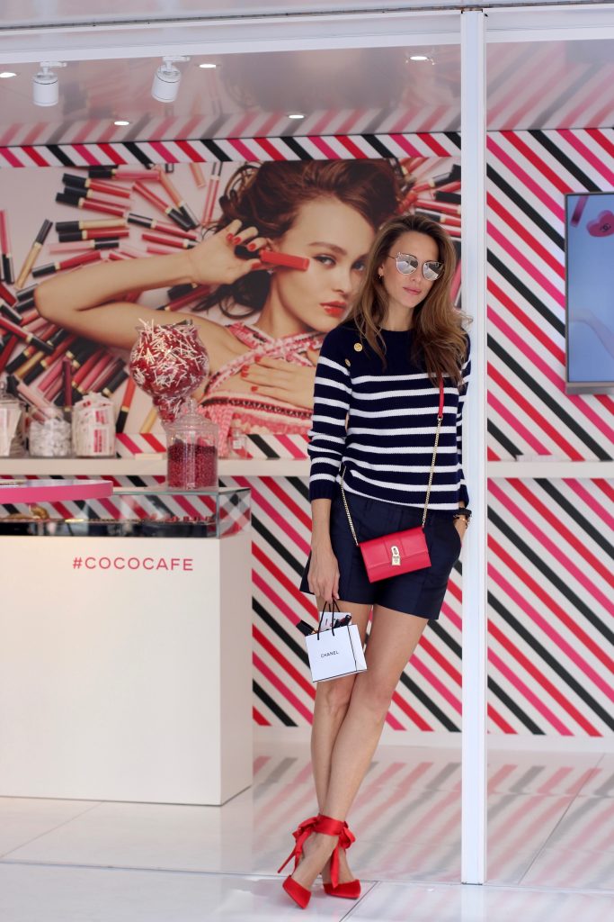 Model and Blogger Alexandra Lapp sitting at Coco Café #cococafe in Duesseldorf, wearing a blue white striped cashmere pullover with gold buttons from Heartbreaker, a dark blue silk shorts by Prada, satin Douce du desert pumps in red with a big silk bow from Christian Louboutin, red crossover purse-bag from Patrizia Pepe and gold cat-eye sunglasses from KARL by Karl Lagerfeld, in Duesseldorf on June, 14th 2017. 