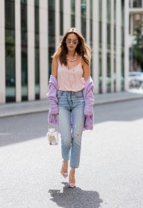 Alexandra Lapp wearing a pastel purple look, a purple cashmere cardigan by Heartbreaker, a rose tank top in silk from Jadicted, a high waist, non-strech denim, five-pocket 501 skinny jeans from Levis, a candy necklace from Chanel supermarket collection in pastel tones, a Chanel perfume bottle bag in plexiglass and a golden chain with white leather, Christian Louboutin pumps Feerica with nude mesh upper embedded with a Swarovski crystal degrade and Karl Lagerfeld cat-eye sunglasses in the shape of cat ears during the Mercedes-Benz Fashion Week Berlin Spring/Summer 2018 on July 7, 2017 in Berlin, Germany.