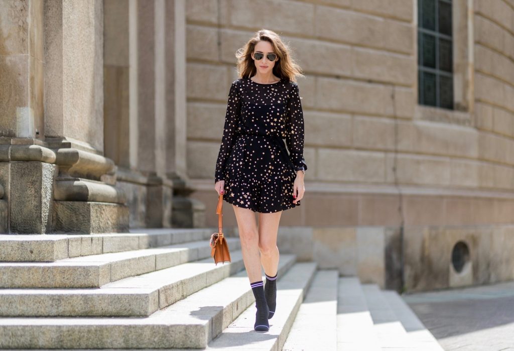 Sock Boots, Fendi, Valentino R.E.D., MCM, Ray Ban, Berlin, MBFWB, MBFW Alexandra Lapp (model, blogger) wearing Fendis SS 17 collection sock boots with a grey knit upper, with a high sculptural heel, a black silk chiffon mini dress with gilded stars from RED Valentino with a tie at the neck and a ruffle through the hem, a MCM Patricia Shoulder Bag crafted in in Visetos-print coated canvas and topped with crystalized appliqués, including the Punk Rabbit, accented with mink fur, studwork and edge painting and a laurel-engraved case latch closure and Ray Ban aviator sunglasses in gold during the Mercedes-Benz Fashion Week Berlin Spring/Summer 2018 on July 6, 2017 in Berlin, Germany.