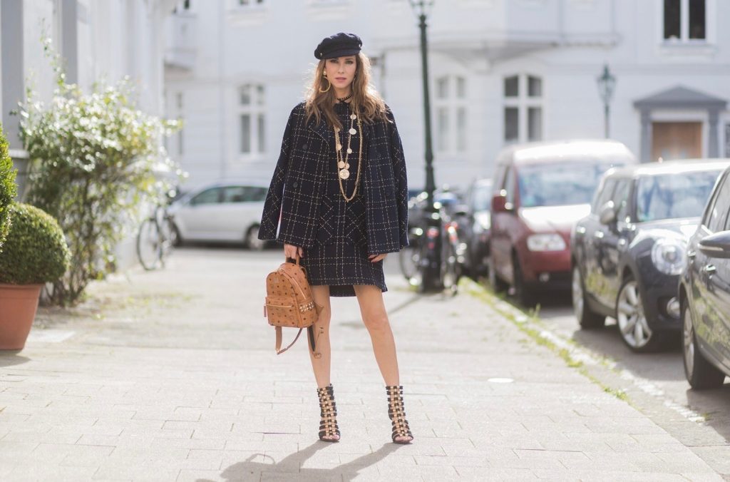 Model and fashion blogger Alexandra Lapp wearing a look inspired by Chanel, a tweed dress and coat from Steffen Schraut, Balmain x HM sandals, Strak backpack by MCM, Chanel tweed cap, golden Chanel chains in form from Chanel coins, Chanel chocker and golden bracelet from Schubart Goldschmiede and golden vintage earrings with a peals by Chanel on August 5, 2017 in Duesseldorf, Germany.