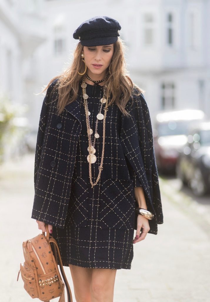 Model and fashion blogger Alexandra Lapp wearing a look inspired by Chanel, a tweed dress and coat from Steffen Schraut, Balmain x HM sandals, Strak backpack by MCM, Chanel tweed cap, golden Chanel chains in form from Chanel coins, Chanel chocker and golden bracelet from Schubart Goldschmiede and golden vintage earrings with a peals by Chanel on August 5, 2017 in Duesseldorf, Germany.