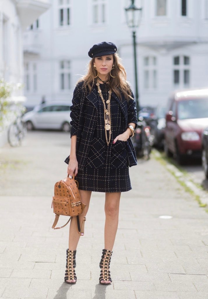 Model and fashion blogger Alexandra Lapp wearing a look inspired by Chanel, a tweed dress and coat from Steffen Schraut, Balmain x HM sandals, Strak backpack by MCM, Chanel tweed cap, golden Chanel chains in form from Chanel coins, Chanel chocker and golden bracelet from Schubart Goldschmiede and golden vintage earrings with a peals by Chanel on August 5, 2017 in Duesseldorf, Germany.