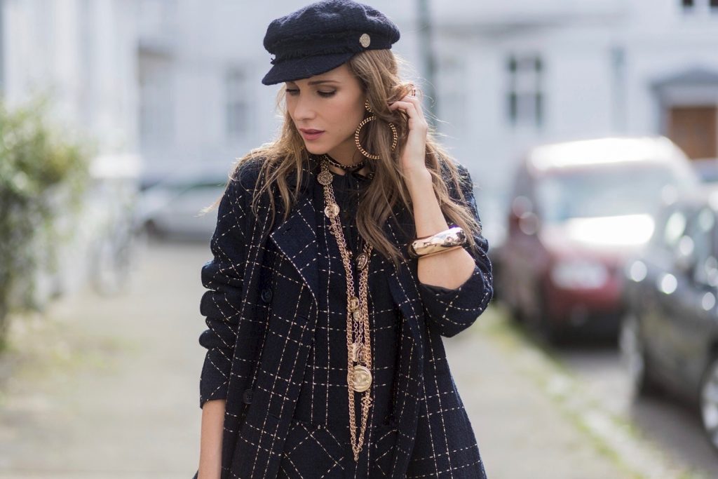 Model and fashion blogger Alexandra Lapp wearing a look inspired by Chanel, a tweed dress and coat from Steffen Schraut, Balmain x HM sandals, Strak backpack by MCM, Chanel tweed cap, golden Chanel chains in form from Chanel coins, Chanel chocker and golden bracelet from Schubart Goldschmiede and golden vintage earrings with a peals by Chanel on August 5, 2017 in Duesseldorf, Germany.