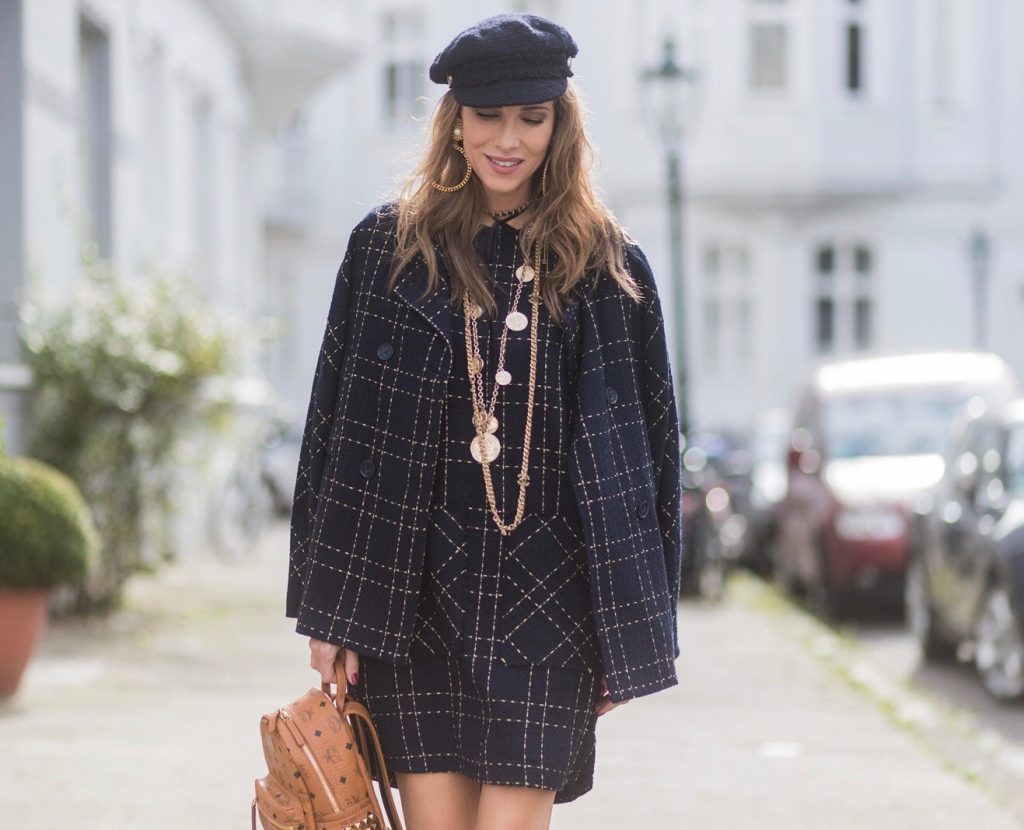 Model and fashion blogger Alexandra Lapp wearing a look inspired by Chanel, a tweed dress and coat from Steffen Schraut, Balmain x HM sandals, Strak backpack by MCM, Chanel tweed cap, golden Chanel chains in form from Chanel coins, Chanel chocker and golden bracelet from Schubart Goldschmiede and golden vintage earrings with a peals by Chanel on August 5, 2017 in Duesseldorf, Germany.