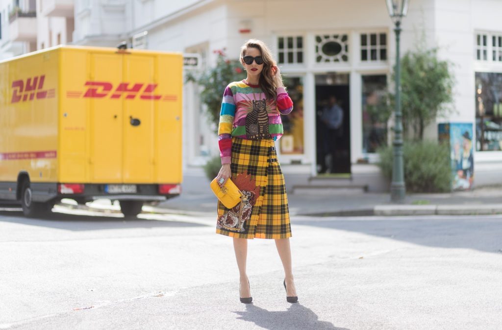 Gucci, Celine, Schubart, Christian Louboutin, Model and Blogger Alexandra Lapp wearing a Gucci total look, yellow and red pleated tartan skirt embroidered with a spaniel dog and belt buckle closure, colorful striped sweater with lace and merino with embroidered cat applique all Gucci, black Christian Louboutin So Kate pumps, GG Marmont Gucci bag in yellow, Audrey sunglasses from Celine on August 4, 2017 in Duesseldorf, Germany.