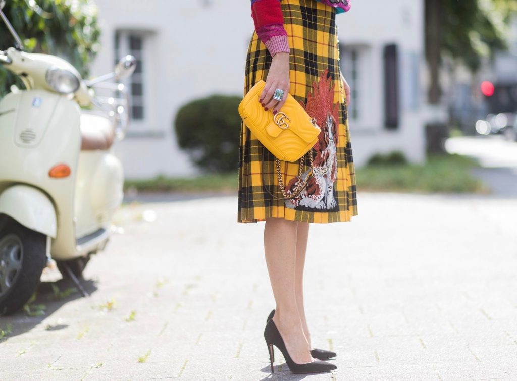 Gucci, Celine, Schubart, Christian Louboutin, Model and Blogger Alexandra Lapp wearing a Gucci total look, yellow and red pleated tartan skirt embroidered with a spaniel dog and belt buckle closure, colorful striped sweater with lace and merino with embroidered cat applique all Gucci, black Christian Louboutin So Kate pumps, GG Marmont Gucci bag in yellow, Audrey sunglasses from Celine on August 4, 2017 in Duesseldorf, Germany.