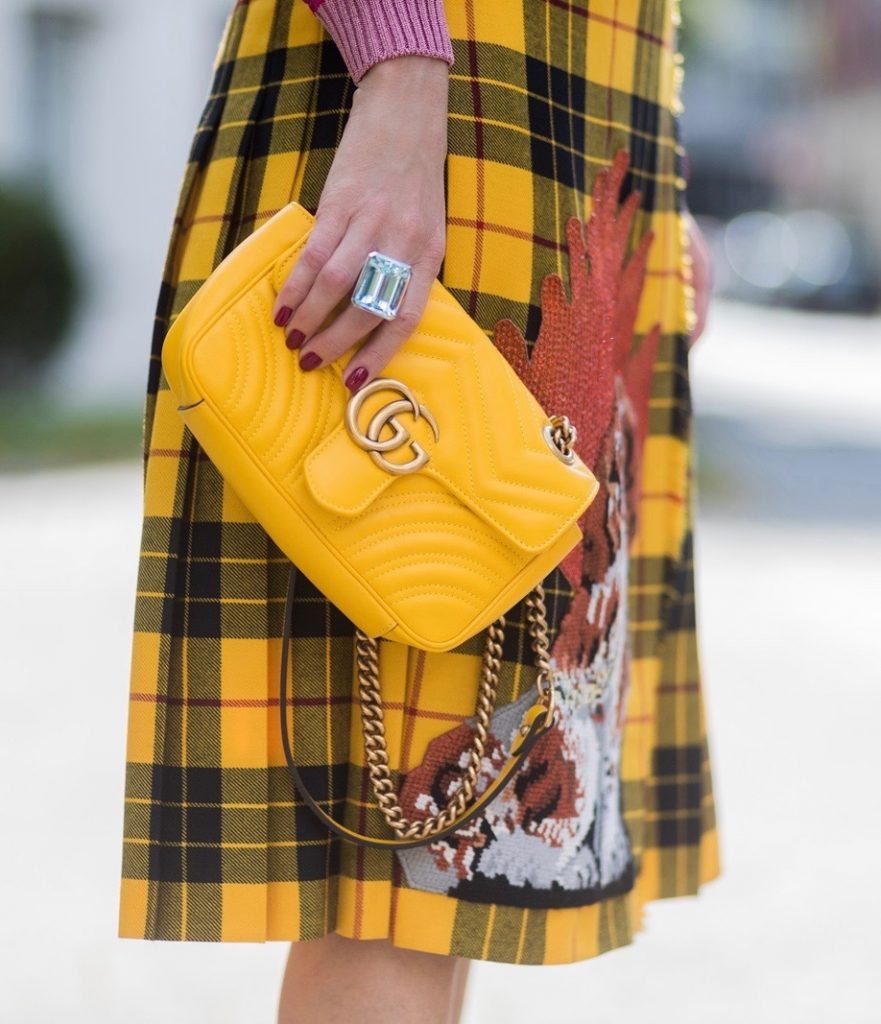 Gucci, Celine, Schubart, Christian Louboutin, Model and Blogger Alexandra Lapp wearing a Gucci total look, yellow and red pleated tartan skirt embroidered with a spaniel dog and belt buckle closure, colorful striped sweater with lace and merino with embroidered cat applique all Gucci, black Christian Louboutin So Kate pumps, GG Marmont Gucci bag in yellow, Audrey sunglasses from Celine on August 4, 2017 in Duesseldorf, Germany.