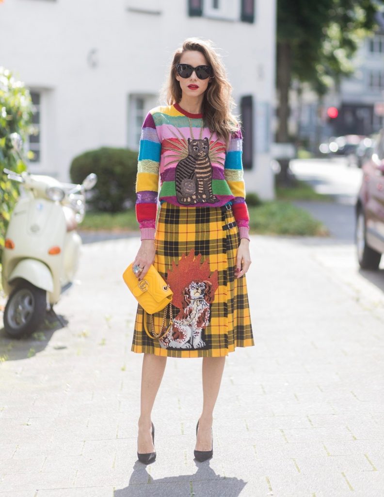 Gucci, Celine, Schubart, Christian Louboutin, Model and Blogger Alexandra Lapp wearing a Gucci total look, yellow and red pleated tartan skirt embroidered with a spaniel dog and belt buckle closure, colorful striped sweater with lace and merino with embroidered cat applique all Gucci, black Christian Louboutin So Kate pumps, GG Marmont Gucci bag in yellow, Audrey sunglasses from Celine on August 4, 2017 in Duesseldorf, Germany.