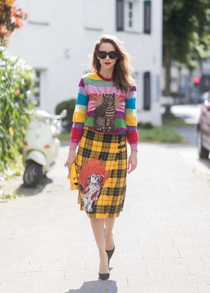 Gucci, Celine, Schubart, Christian Louboutin, Model and Blogger Alexandra Lapp wearing a Gucci total look, yellow and red pleated tartan skirt embroidered with a spaniel dog and belt buckle closure, colorful striped sweater with lace and merino with embroidered cat applique all Gucci, black Christian Louboutin So Kate pumps, GG Marmont Gucci bag in yellow, Audrey sunglasses from Celine on August 4, 2017 in Duesseldorf, Germany.