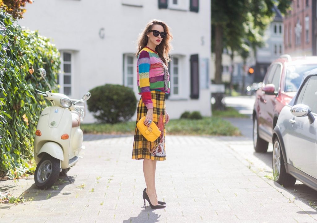 Gucci, Celine, Schubart, Christian Louboutin, Model and Blogger Alexandra Lapp wearing a Gucci total look, yellow and red pleated tartan skirt embroidered with a spaniel dog and belt buckle closure, colorful striped sweater with lace and merino with embroidered cat applique all Gucci, black Christian Louboutin So Kate pumps, GG Marmont Gucci bag in yellow, Audrey sunglasses from Celine on August 4, 2017 in Duesseldorf, Germany.