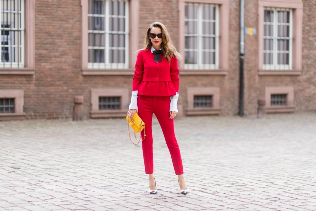 Model and fashion blogger Alexandra Lapp wearing a slim fit, red suit from Steffen Schraut, blazer with peplum and red pants, white blouse with a black ribbon bow from Steffen Schraut, white pumps with black toecap from Saint Laurent, Chanel sunglasses with pearls and yellow GG Marmont bag from Gucci on August 5, 2017 in Duesseldorf, Germany.