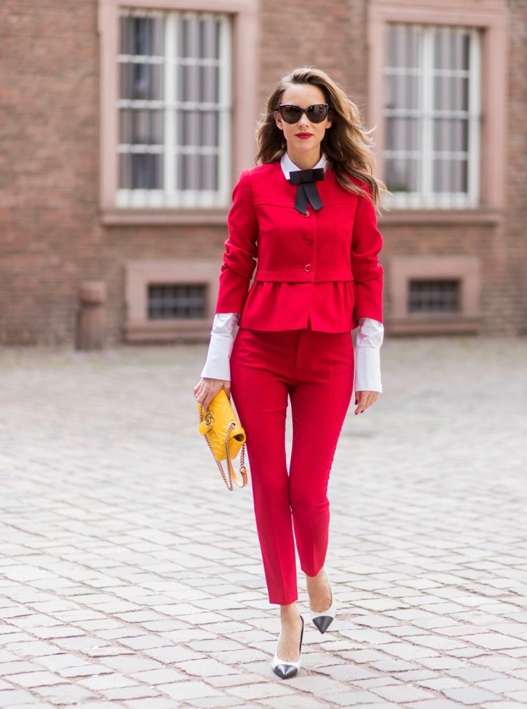 Model and fashion blogger Alexandra Lapp wearing a slim fit, red suit from Steffen Schraut, blazer with peplum and red pants, white blouse with a black ribbon bow from Steffen Schraut, white pumps with black toecap from Saint Laurent, Chanel sunglasses with pearls and yellow GG Marmont bag from Gucci on August 5, 2017 in Duesseldorf, Germany.