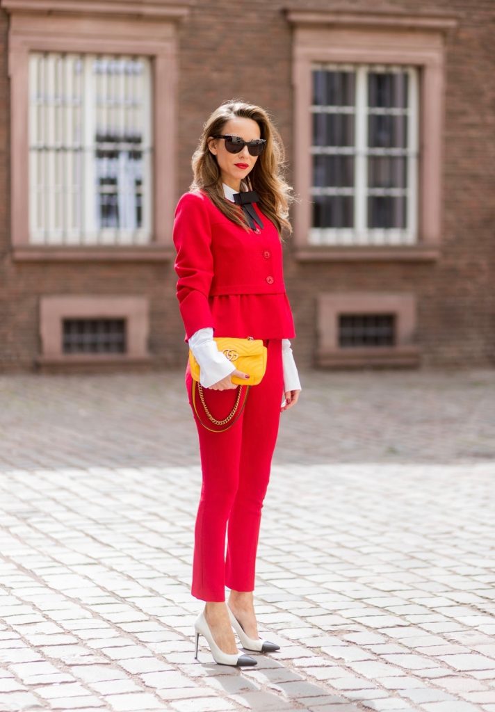 Model and fashion blogger Alexandra Lapp wearing a slim fit, red suit from Steffen Schraut, blazer with peplum and red pants, white blouse with a black ribbon bow from Steffen Schraut, white pumps with black toecap from Saint Laurent, Chanel sunglasses with pearls and yellow GG Marmont bag from Gucci on August 5, 2017 in Duesseldorf, Germany.