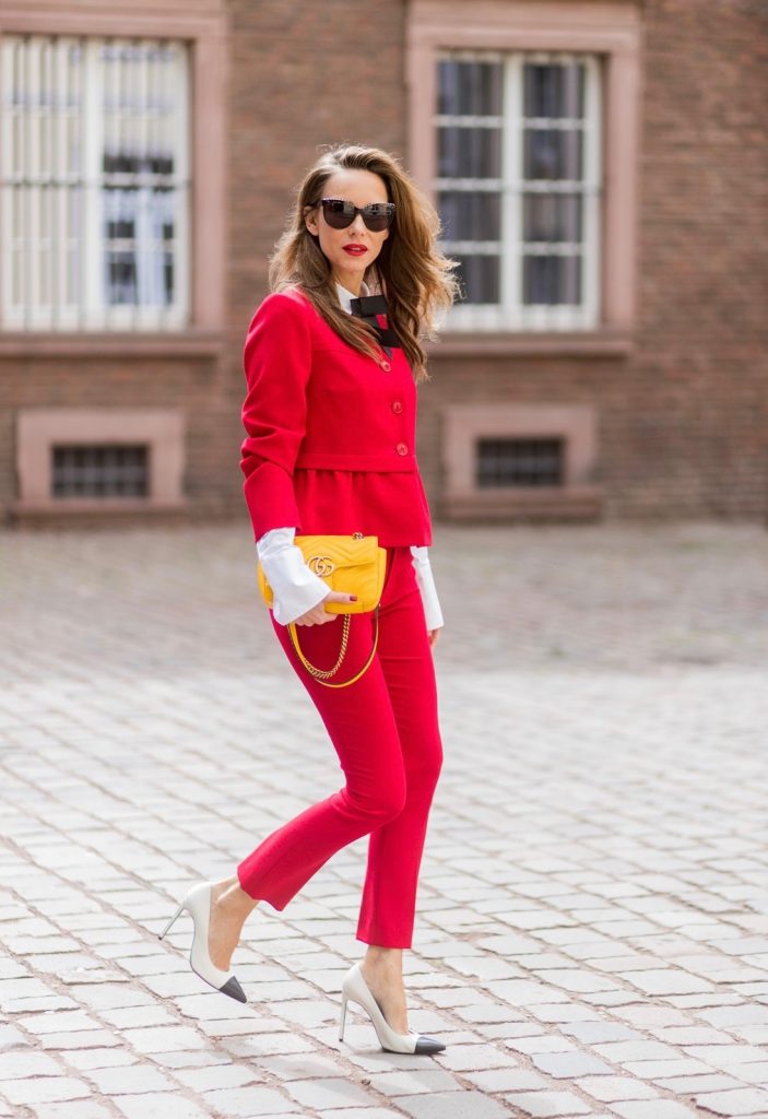 Model and fashion blogger Alexandra Lapp wearing a slim fit, red suit from Steffen Schraut, blazer with peplum and red pants, white blouse with a black ribbon bow from Steffen Schraut, white pumps with black toecap from Saint Laurent, Chanel sunglasses with pearls and yellow GG Marmont bag from Gucci on August 5, 2017 in Duesseldorf, Germany.