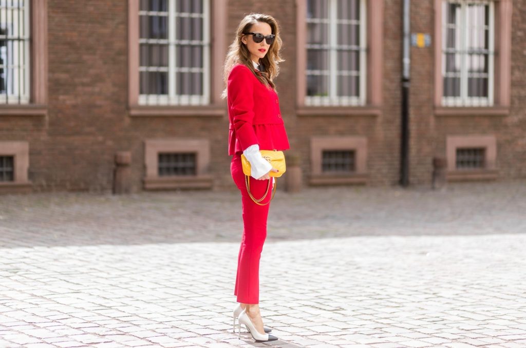Model and fashion blogger Alexandra Lapp wearing a slim fit, red suit from Steffen Schraut, blazer with peplum and red pants, white blouse with a black ribbon bow from Steffen Schraut, white pumps with black toecap from Saint Laurent, Chanel sunglasses with pearls and yellow GG Marmont bag from Gucci on August 5, 2017 in Duesseldorf, Germany.