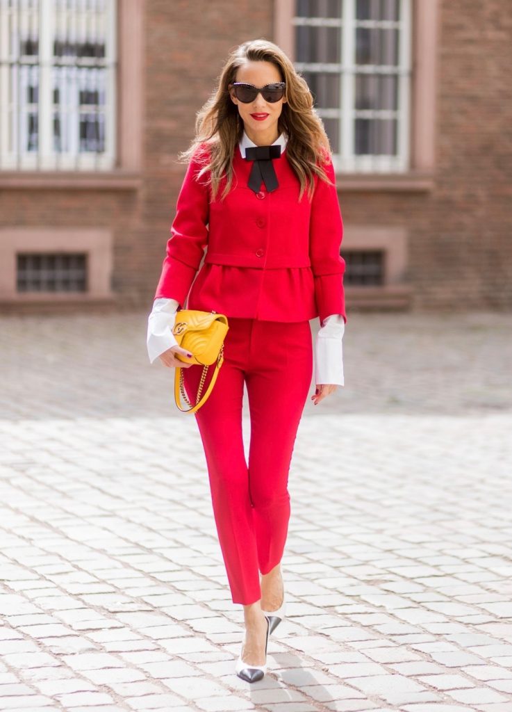Model and fashion blogger Alexandra Lapp wearing a slim fit, red suit from Steffen Schraut, blazer with peplum and red pants, white blouse with a black ribbon bow from Steffen Schraut, white pumps with black toecap from Saint Laurent, Chanel sunglasses with pearls and yellow GG Marmont bag from Gucci on August 5, 2017 in Duesseldorf, Germany.