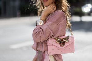 Model and fashion blogger Alexandra Lapp wearing metallic chic, pleated lame skirt in shimmering pastel, pink metallic v-neck knit by Alberta Ferretti, Christian Louboutin Feerica heels with Swarovski crystals and flower accessory, pink Broadway leather bag with pearl studs, Le Specs sunglasses, bracelet and rose gold ring with baguette diamonds by Schubart on August 4, 2017 in Duesseldorf, Germany.