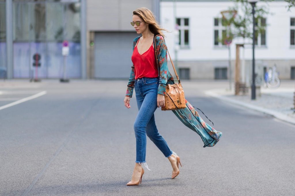Model and fashion blogger Alexandra Lapp wearing a wrap dress in Kimono style from Zara, silk tank top from Jadicted, petite bucket bag from MCM, Levis Wedgie Icon Fit jeans in slim fit, So Kate pumps in cognac by Christian Louboutin and gold mirrored aviator sunglasses by Thom Browne during the Mercedes-Benz Fashion Week Berlin Spring/Summer 2018 on July 8, 2017 in Berlin, Germany.
