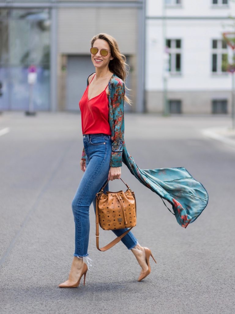 Model and fashion blogger Alexandra Lapp wearing a wrap dress in Kimono style from Zara, silk tank top from Jadicted, petite bucket bag from MCM, Levis Wedgie Icon Fit jeans in slim fit, So Kate pumps in cognac by Christian Louboutin and gold mirrored aviator sunglasses by Thom Browne during the Mercedes-Benz Fashion Week Berlin Spring/Summer 2018 on July 8, 2017 in Berlin, Germany.