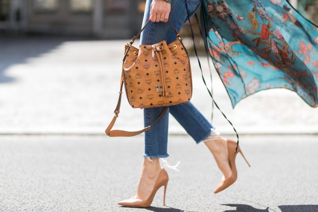 Model and fashion blogger Alexandra Lapp wearing a wrap dress in Kimono style from Zara, silk tank top from Jadicted, petite bucket bag from MCM, Levis Wedgie Icon Fit jeans in slim fit, So Kate pumps in cognac by Christian Louboutin and gold mirrored aviator sunglasses by Thom Browne during the Mercedes-Benz Fashion Week Berlin Spring/Summer 2018 on July 8, 2017 in Berlin, Germany.