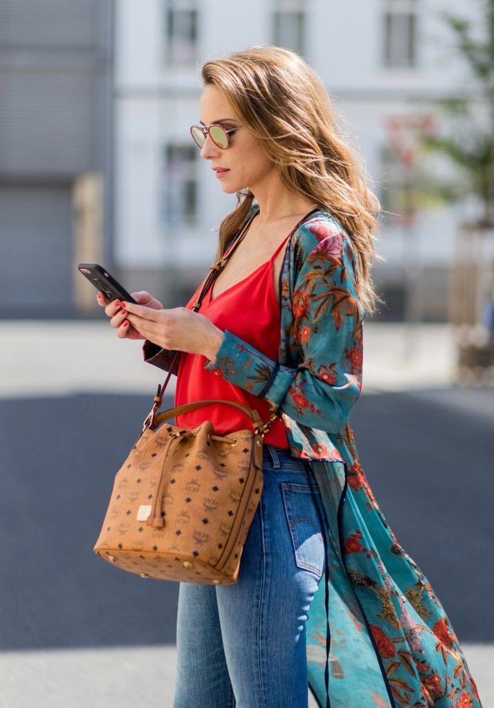 Model and fashion blogger Alexandra Lapp wearing a wrap dress in Kimono style from Zara, silk tank top from Jadicted, petite bucket bag from MCM, Levis Wedgie Icon Fit jeans in slim fit, So Kate pumps in cognac by Christian Louboutin and gold mirrored aviator sunglasses by Thom Browne during the Mercedes-Benz Fashion Week Berlin Spring/Summer 2018 on July 8, 2017 in Berlin, Germany.