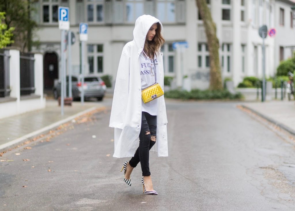 Couple look a like holding arms in front of a DHL van - Model and Blogger Alexandra Lapp wearing oversized Vetements raincoat with a hood in white, Vetements hoodie in white, destroyed Adriano Goldschmied high waist denim in black, black and white So Kate pumps with a yellow heel, yellow golden lacquer Boy bag from Chanel and a big golden ring with baguette diamonds from Schubart Goldschmiede and Model and Blogger Thomas Stuch wearing black oversized raincoat with a hood in black from Vetements, Stella McCartney hoodie in black, Dsquared slim fit denim, Ghost cowboy boots on August 4, 2017 in Duesseldorf, Germany.