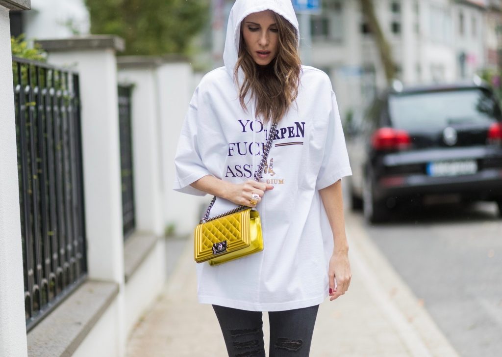 Couple look a like holding arms in front of a DHL van - Model and Blogger Alexandra Lapp wearing oversized Vetements raincoat with a hood in white, Vetements hoodie in white, destroyed Adriano Goldschmied high waist denim in black, black and white So Kate pumps with a yellow heel, yellow golden lacquer Boy bag from Chanel and a big golden ring with baguette diamonds from Schubart Goldschmiede and Model and Blogger Thomas Stuch wearing black oversized raincoat with a hood in black from Vetements, Stella McCartney hoodie in black, Dsquared slim fit denim, Ghost cowboy boots on August 4, 2017 in Duesseldorf, Germany.