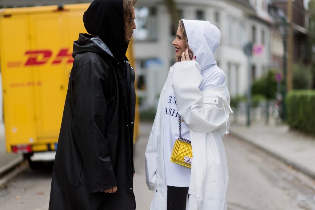 Couple look a like holding arms in front of a DHL van - Model and Blogger Alexandra Lapp wearing oversized Vetements raincoat with a hood in white, Vetements hoodie in white, destroyed Adriano Goldschmied high waist denim in black, black and white So Kate pumps with a yellow heel, yellow golden lacquer Boy bag from Chanel and a big golden ring with baguette diamonds from Schubart Goldschmiede and Model and Blogger Thomas Stuch wearing black oversized raincoat with a hood in black from Vetements, Stella McCartney hoodie in black, Dsquared slim fit denim, Ghost cowboy boots on August 4, 2017 in Duesseldorf, Germany.