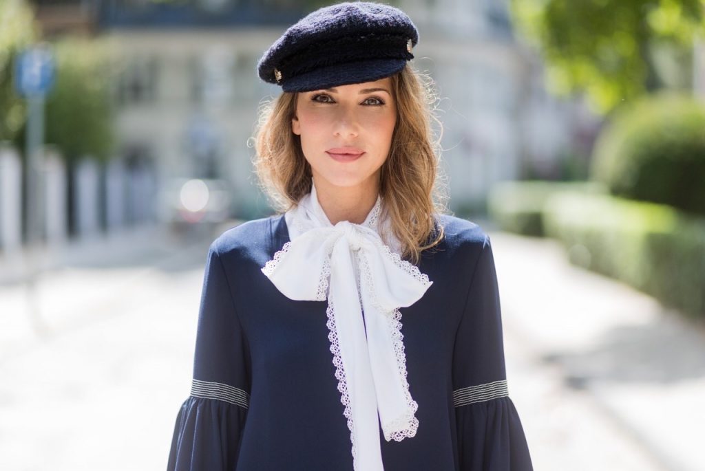 Model and fashion blogger Alexandra Lapp wearing a navy dress with oversized sleeves and a white tie-neck blouse from Steffen Schraut, Chanel tweed cap, baroque Fendi sock-boots in black and white, Chanel 2.55 classic back in white leather with black pearls on August 4, 2017 in Duesseldorf, Germany. 