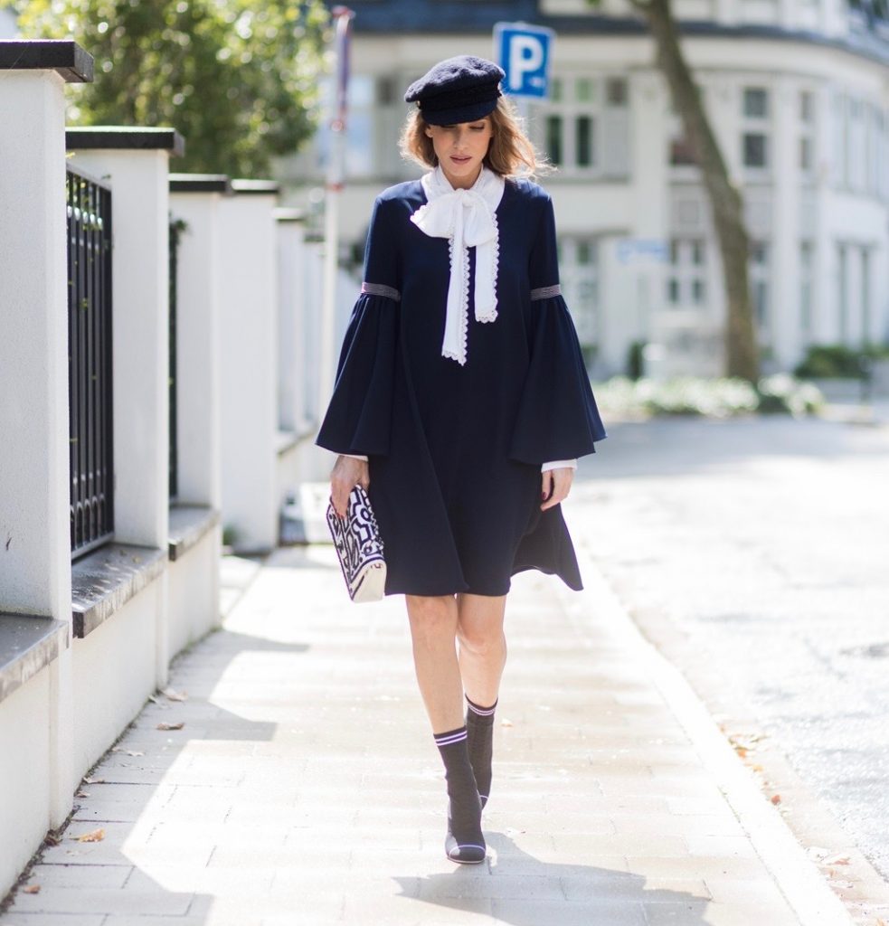 Model and fashion blogger Alexandra Lapp wearing a navy dress with oversized sleeves and a white tie-neck blouse from Steffen Schraut, Chanel tweed cap, baroque Fendi sock-boots in black and white, Chanel 2.55 classic back in white leather with black pearls on August 4, 2017 in Duesseldorf, Germany. 